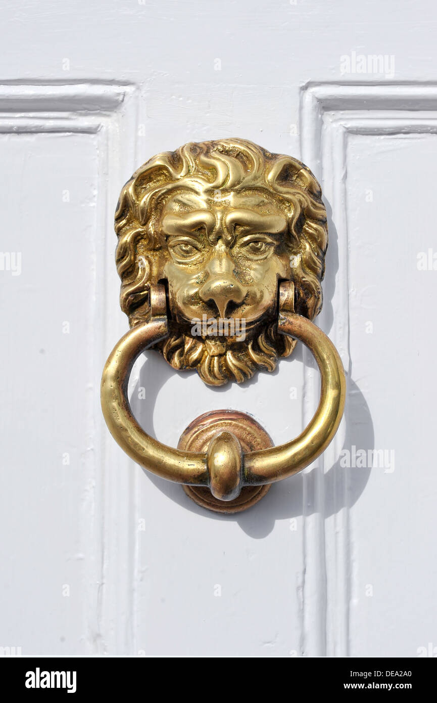 A lions head door knocker on a white painted paneled door Stock Photo