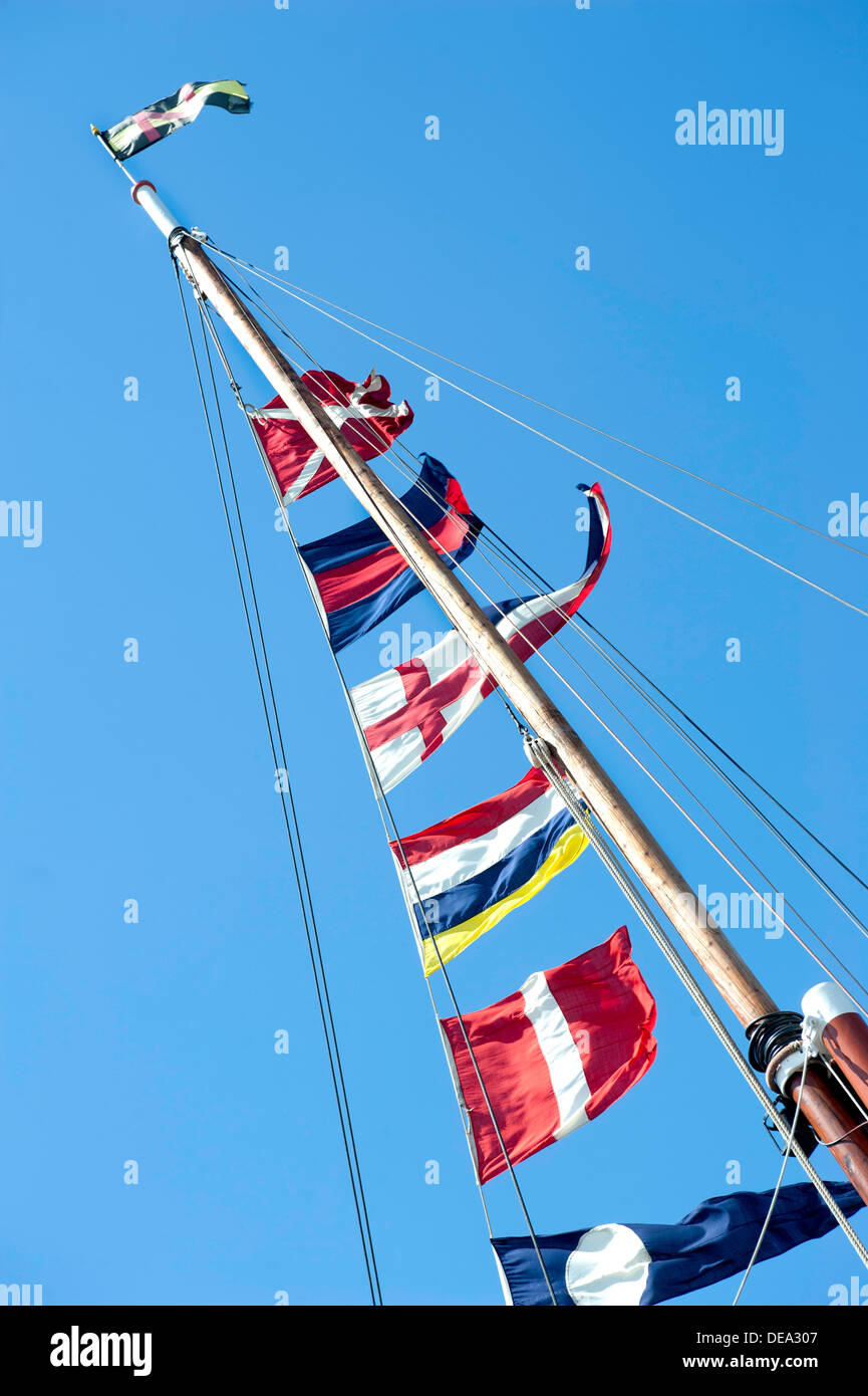 Seen from below a selection of colourful ships flags up a mast and fluttering in the wind Stock Photo