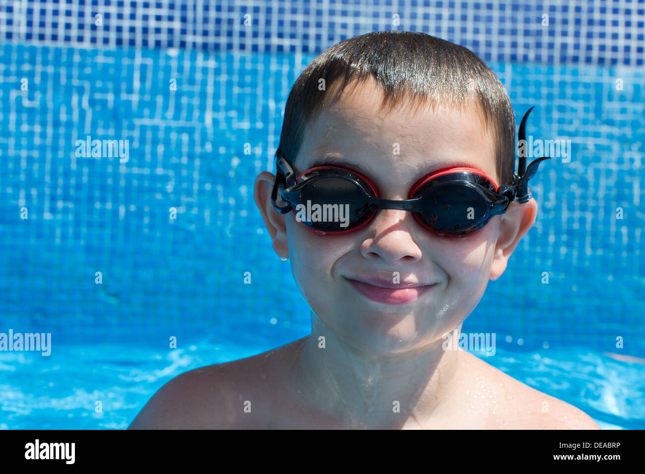 Eight years old kid in the swimming pool looking with his goggles Stock