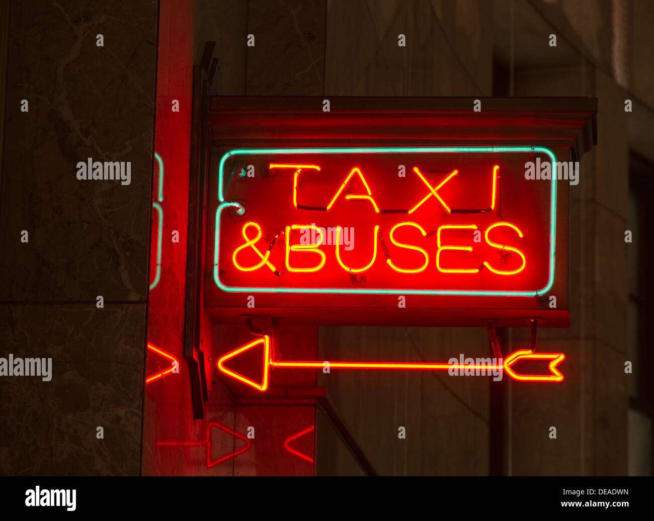 A red neon sign points the way to transportation Stock Photo