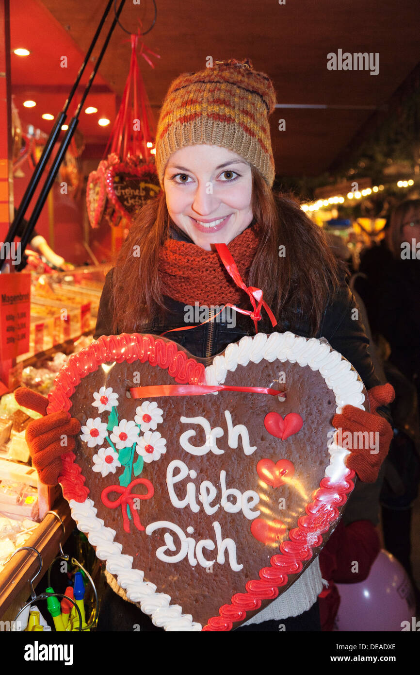 Young woman with a gingerbread heart at Christmas fair, Esslingen, Baden Wurttemberg, Germany Stock Photo