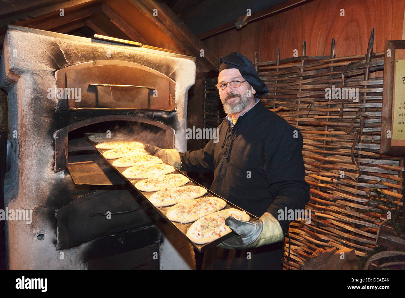 Man put tarte flambee into the oven, Christmas fair, Medieval Market,  Esslingen, Baden Wurttemberg, Germany Stock Photo