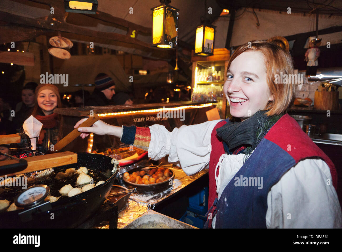 Young woman at a stand cooking food at the Medieval market at the Christmas fair, Esslingen, Baden Wurttemberg, Germany Stock Photo