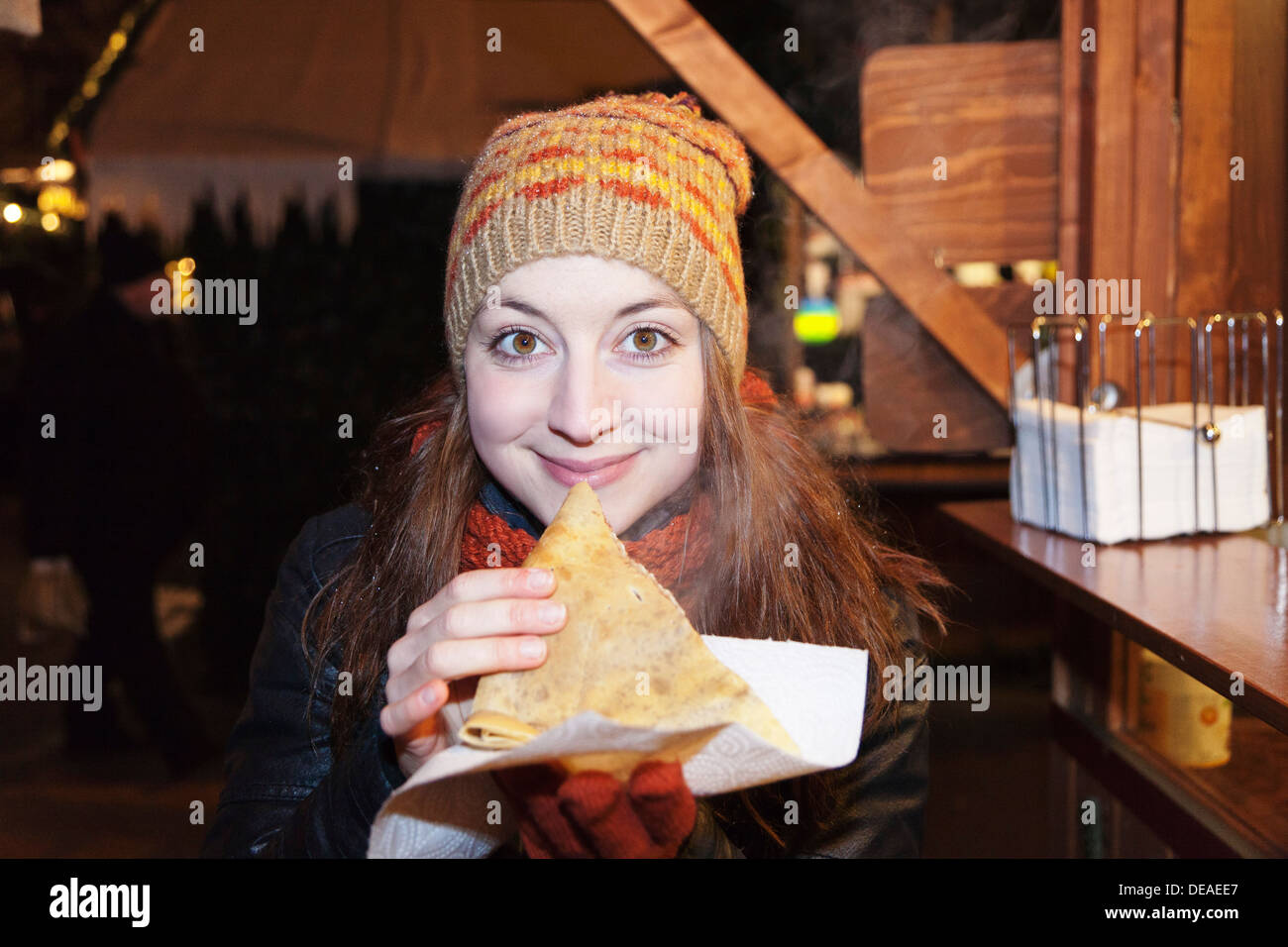 Young woman at the Christmas fair eating crepes, Esslingen, Baden Wurttemberg, Germany Stock Photo