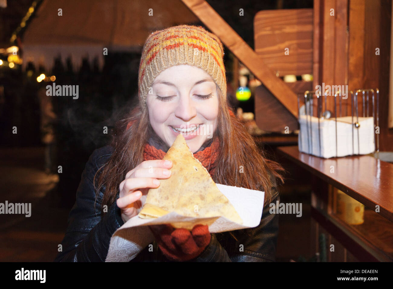 Young woman at the Christmas fair eating crepes, Esslingen, Baden Wurttemberg, Germany Stock Photo