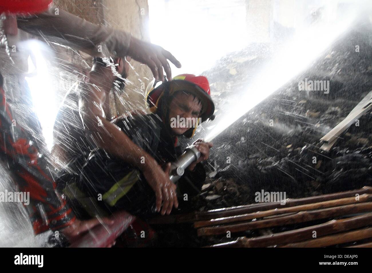 Firefighter with the help of local youths from a distance sprays water ...