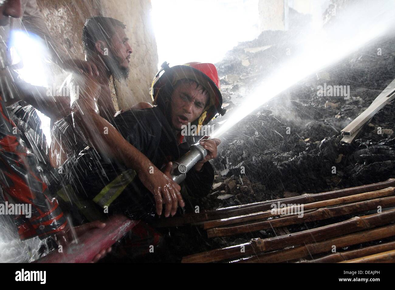 Firefighter with the help of local youths from a distance sprays water