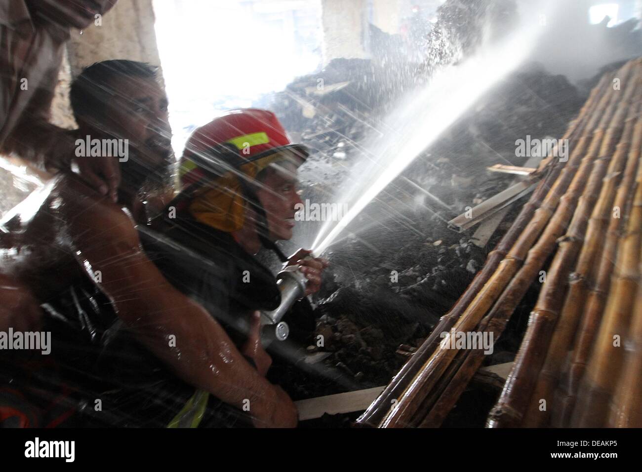 Firefighter with the help of local youths from a distance sprays water ...