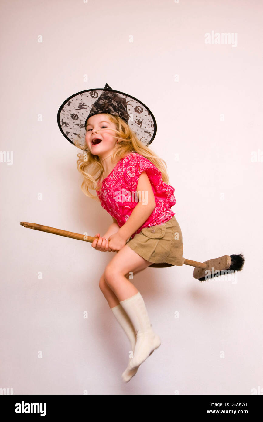 Girl, 5 years, with witch's hat flying on broom Stock Photo