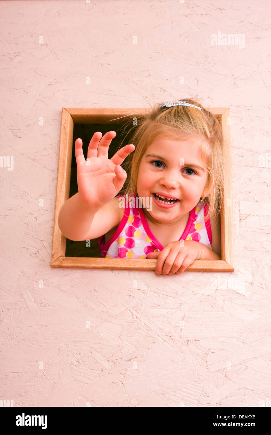 Girl, 3 years, waving through window Stock Photo