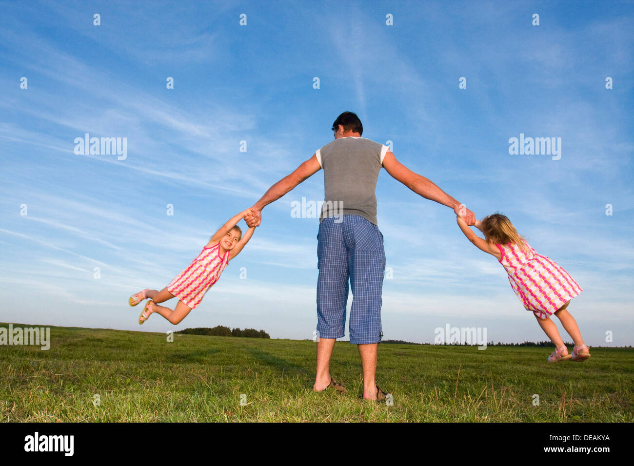 Twin girls, 3 years, playing with their father, 29 years, outdoors Stock Photo