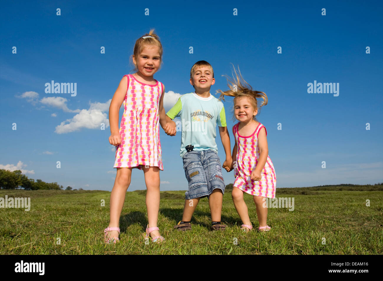 Twin girls, 3 years, and their brother, 7 years, outdoors Stock Photo
