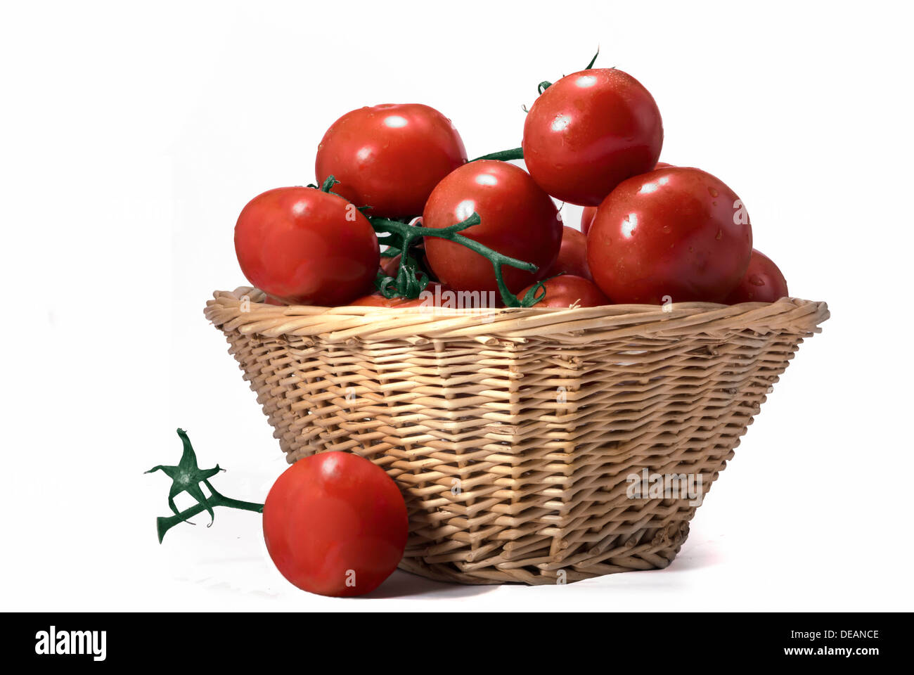 A wicker basket overflowing with ripe tomatoes Stock Photo