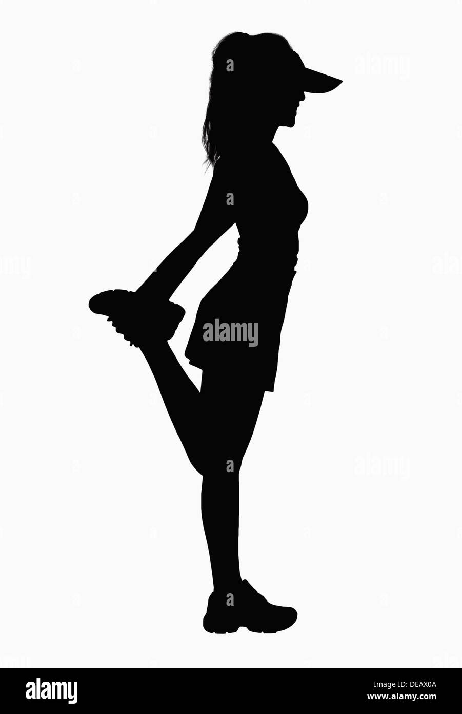 Silhouette of woman stretching leg. Stock Photo
