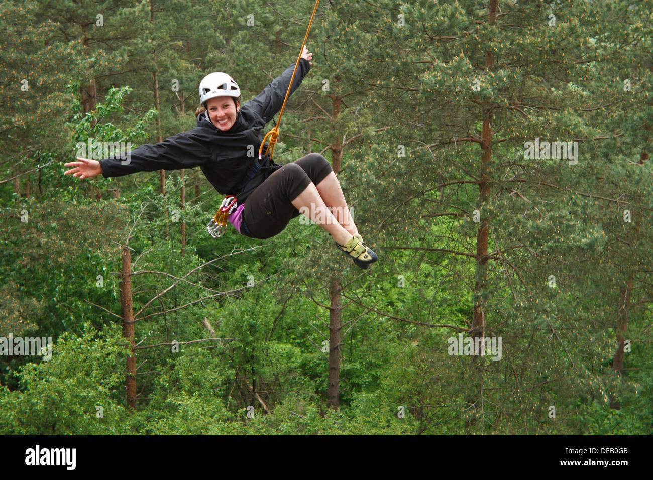 Young female climber hanging on the rope, happy after successful