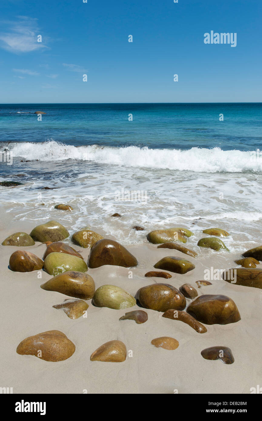 Beach with rocks polished smooth by the sea ocean in the background, Victoria Road south of Cape Town, South Africa Stock Photo