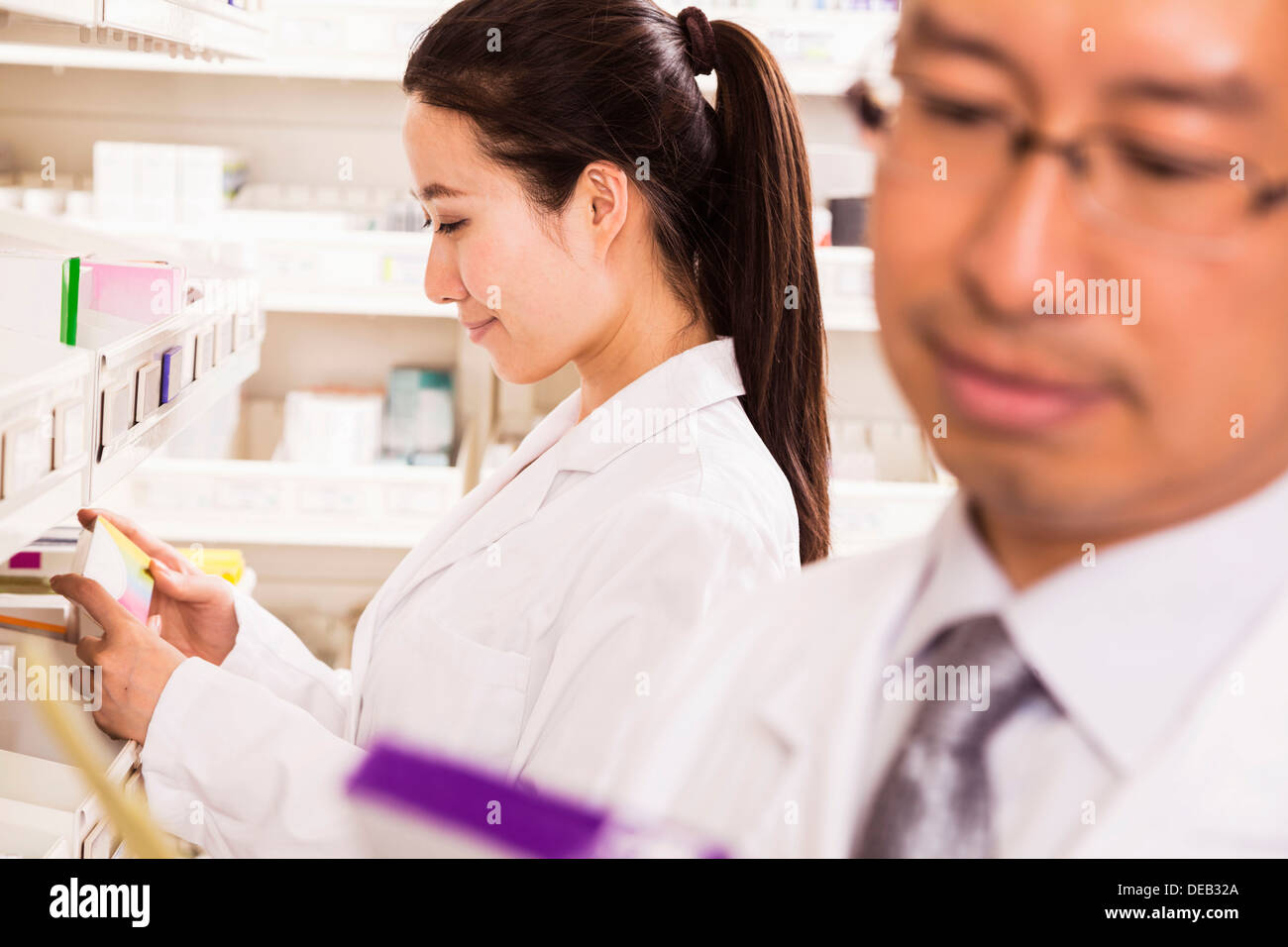 Pharmacist taking down and examining prescription medication in a pharmacy Stock Photo