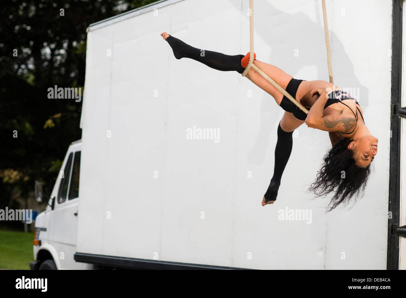 A woman trapeze artist entertainer performing by her truck at a summer party at a country house hotel UK Stock Photo