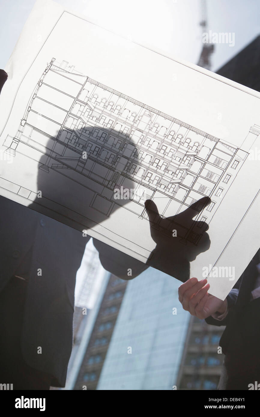 Two architects looking at blueprint on construction site Stock Photo