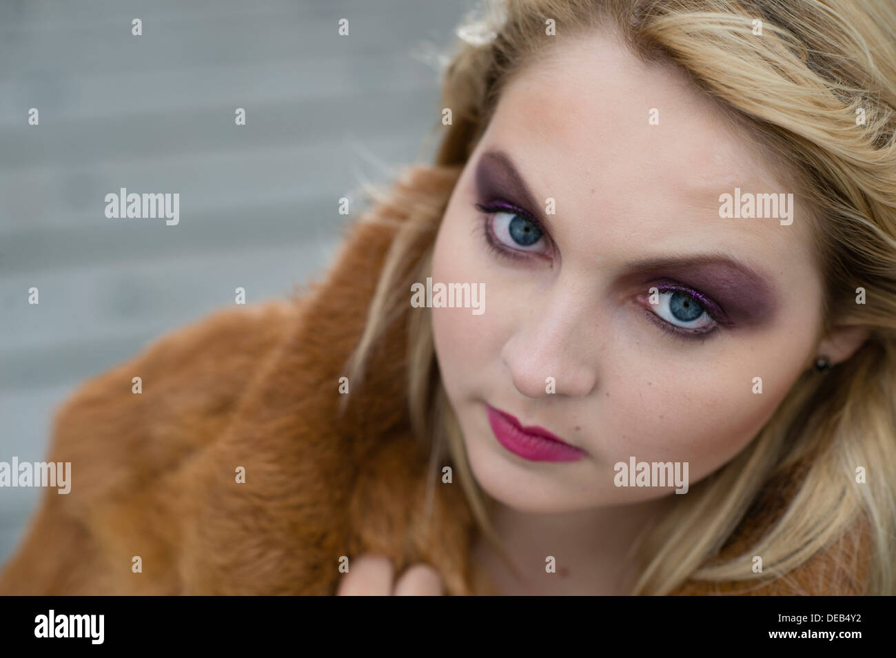 a young blond blonde woman teenage girl wearing a fur coat looking at camera with big eyes, UK Stock Photo