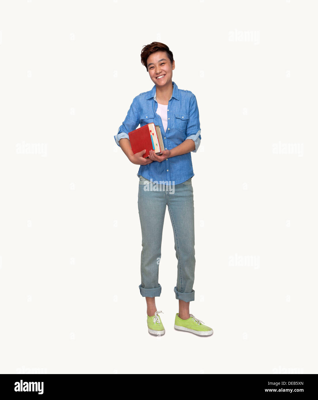 Portrait of smiling young female student holding books, studio shot ...