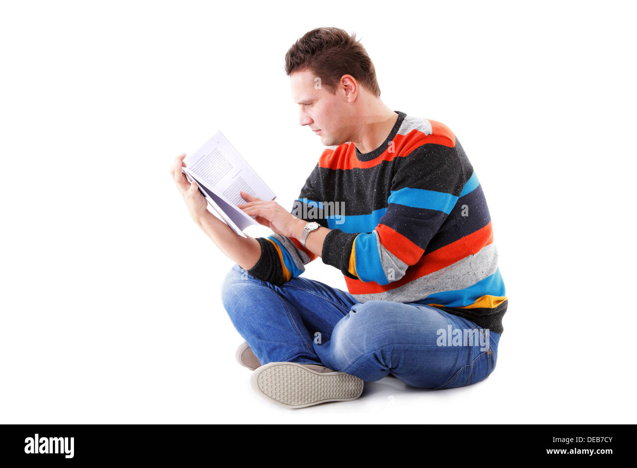 Portrait of a male student sitting reading a book isolated on white Stock Photo