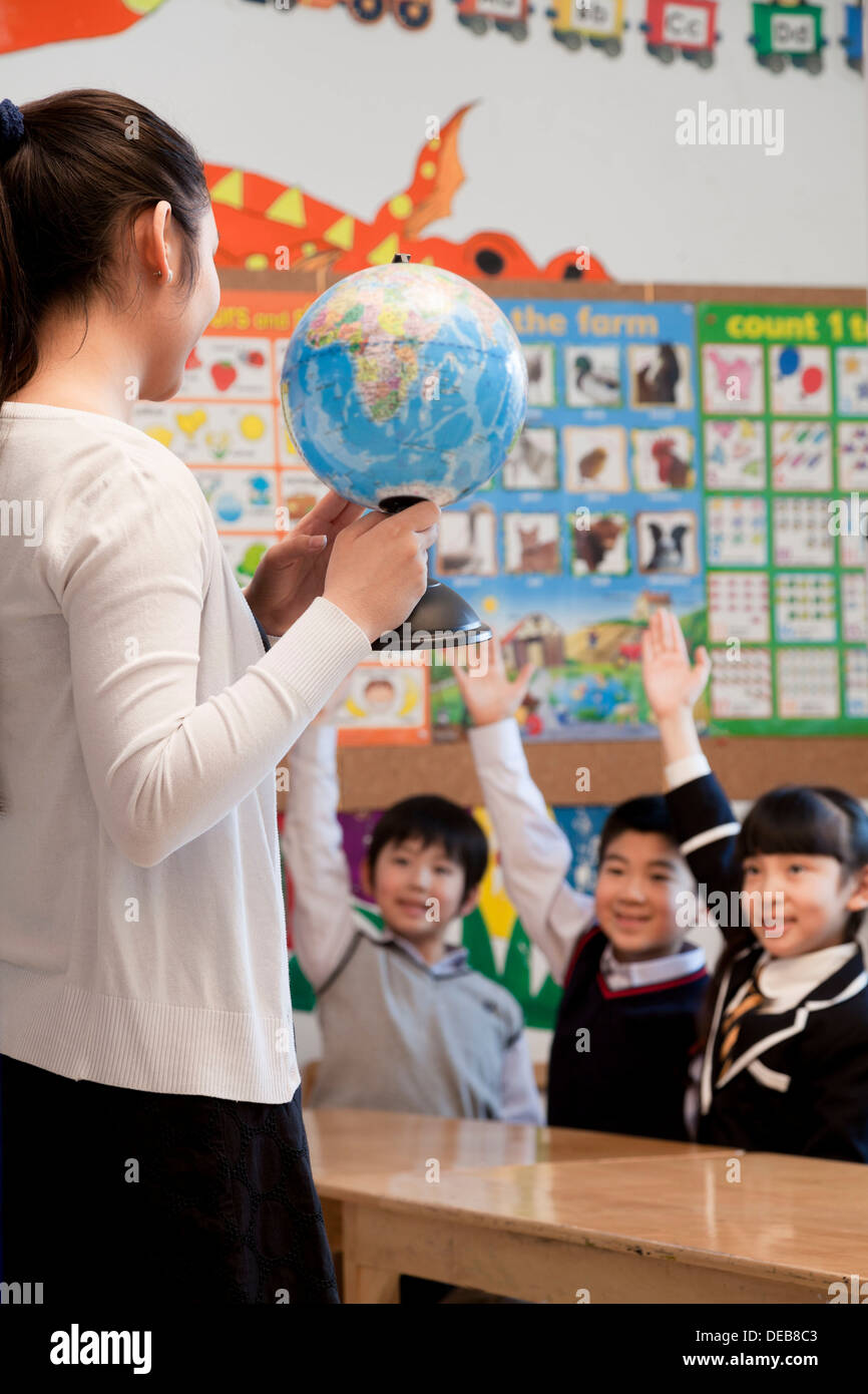 Teacher teaching geography to schoolchildren with a globe Stock Photo Alamy