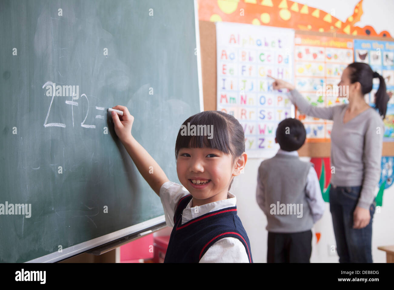 Schoolgirl doing math equation on the black board Stock Photo