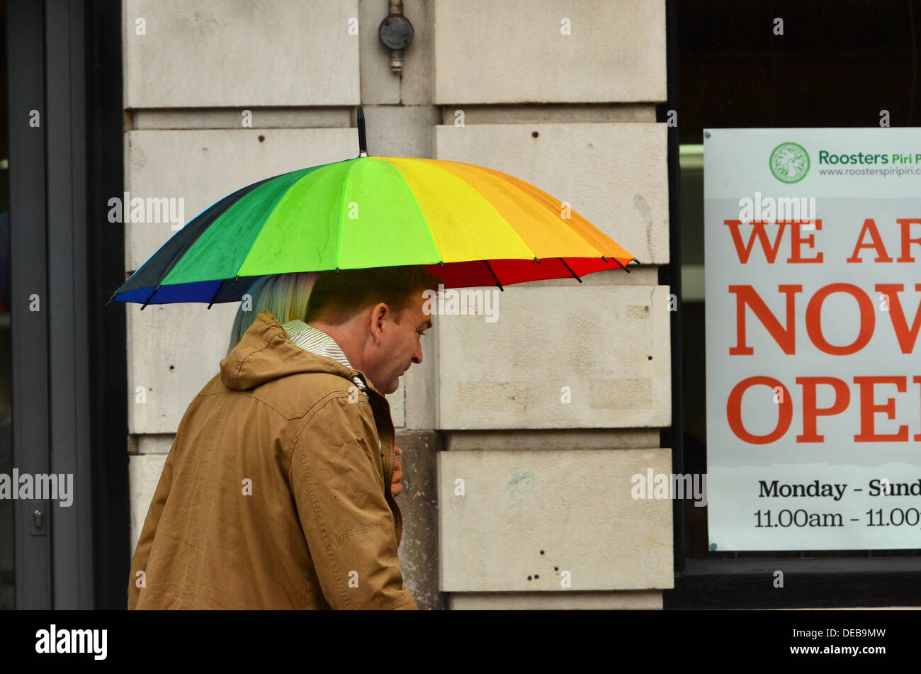 a couple share an umbrella in the rain at the high street Stock Photo
