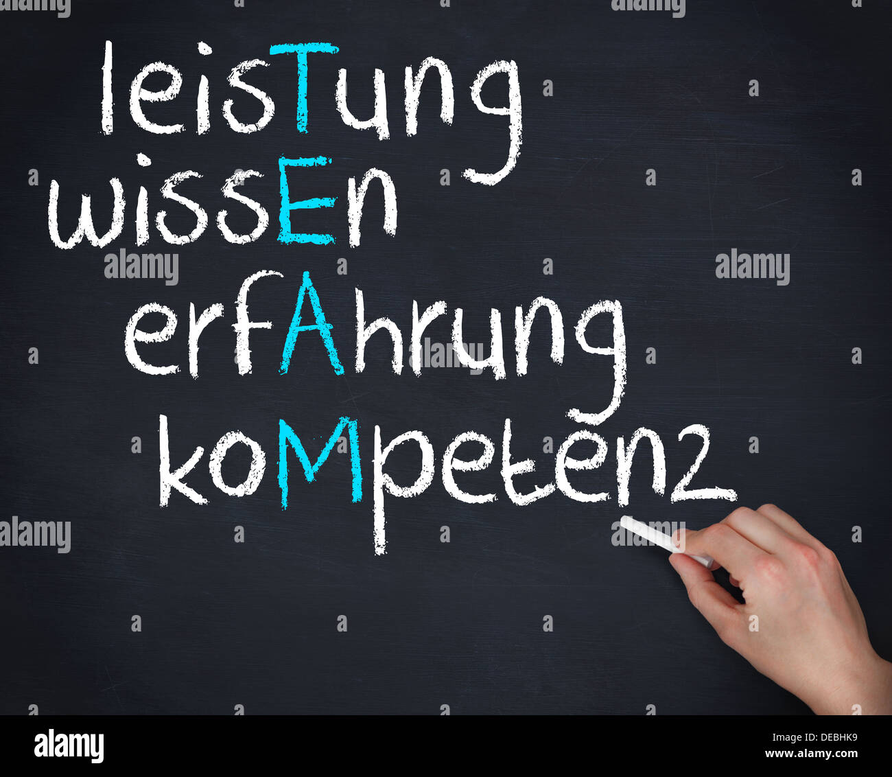 Hand holding a chalk and writing team anagram in german Stock Photo