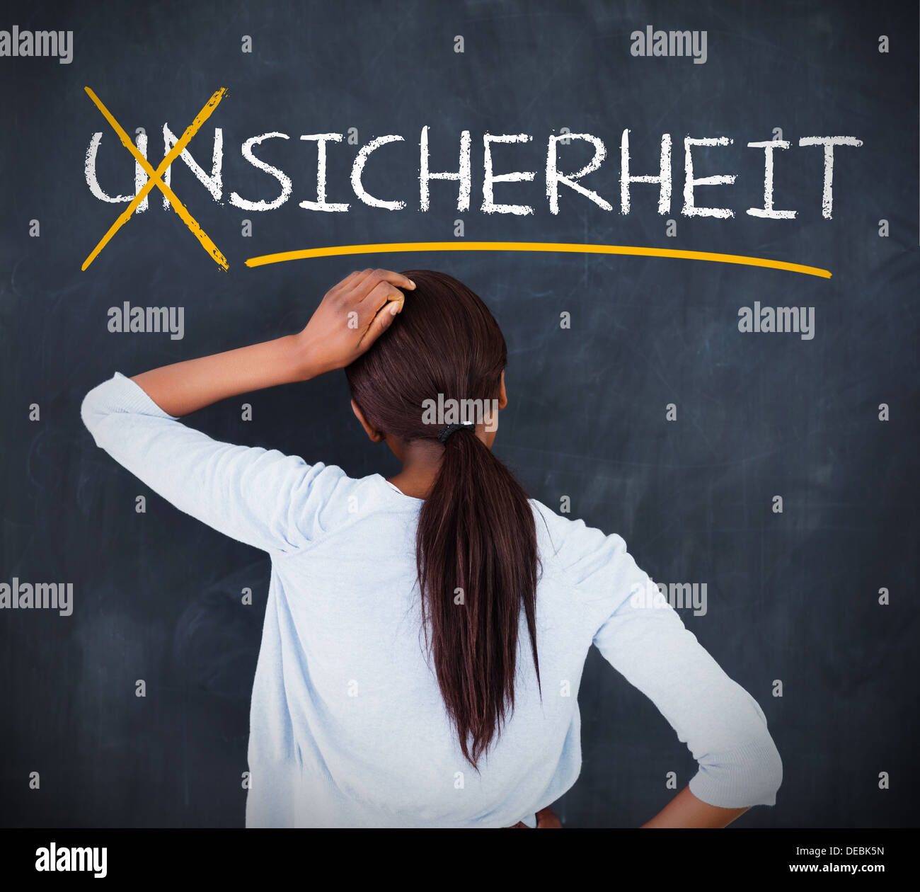Woman looking at a chalkboard with sicherheit on it Stock Photo