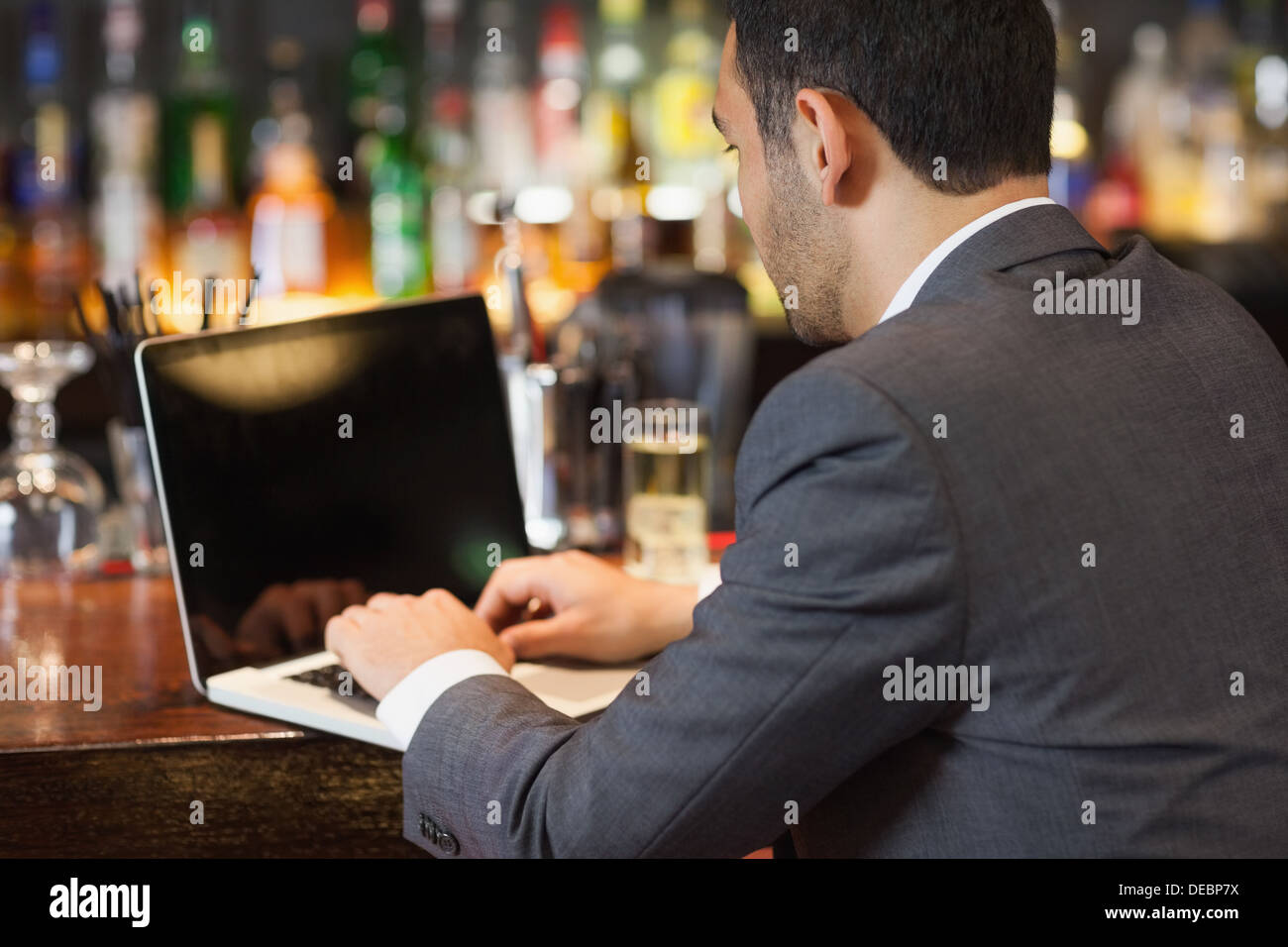 Handsome businessman working on his laptop while having a drink Stock Photo