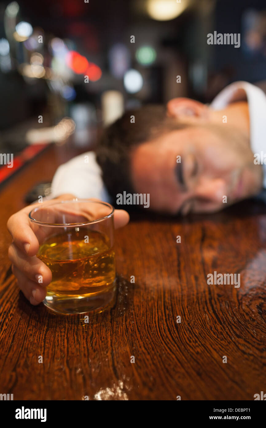 Drunk businessman holding whiskey lying on a counter Stock Photo Alamy