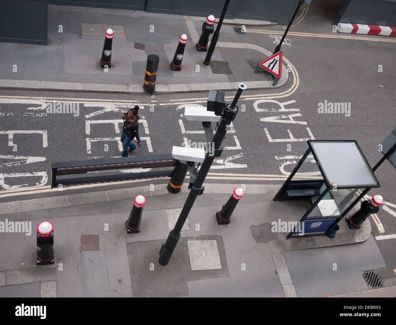 woman walking past city of London UK surveillance cctv cameras in street Stock Photo