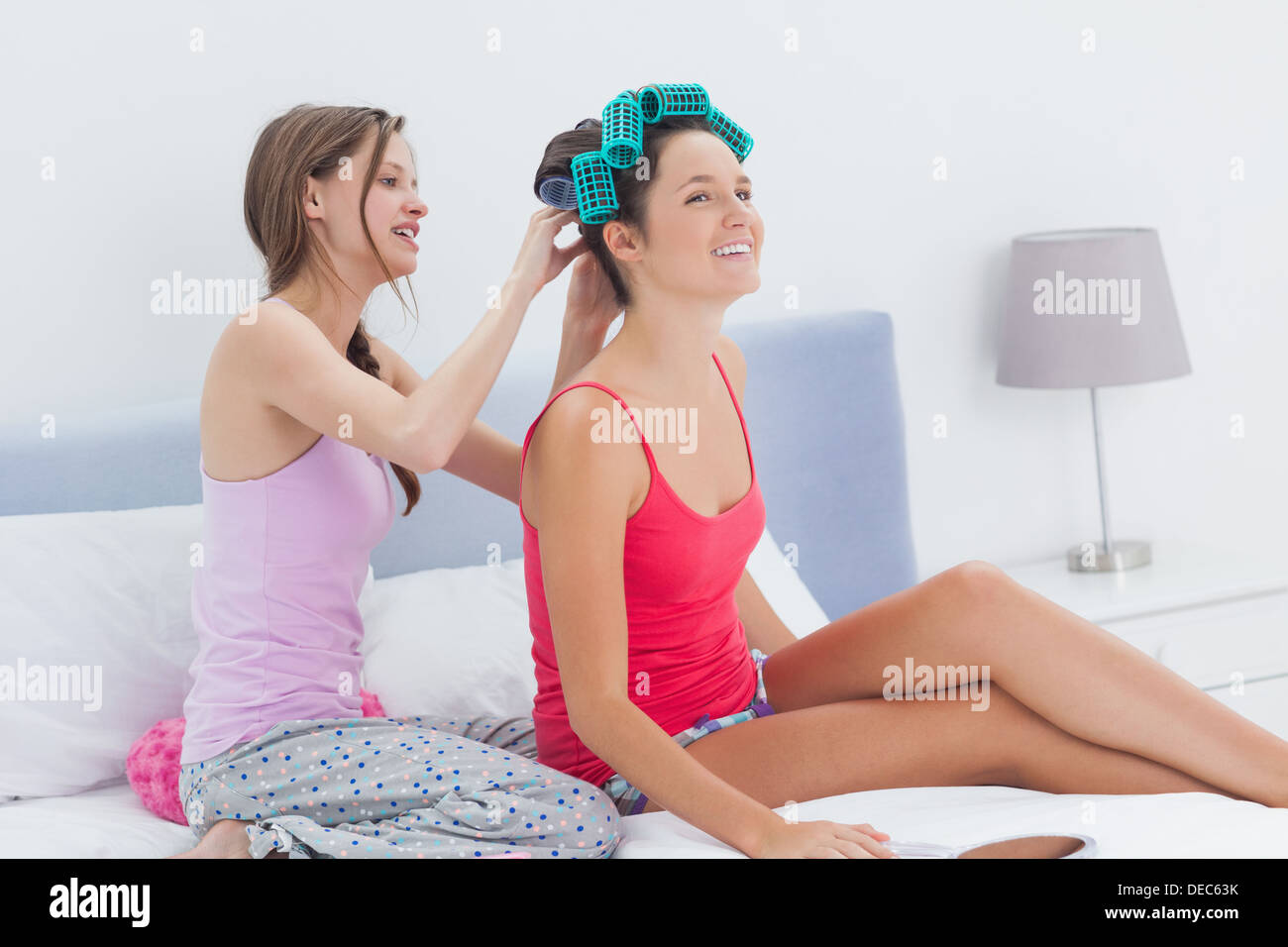 Girls sitting in bed one wearing hair rollers Stock Photo