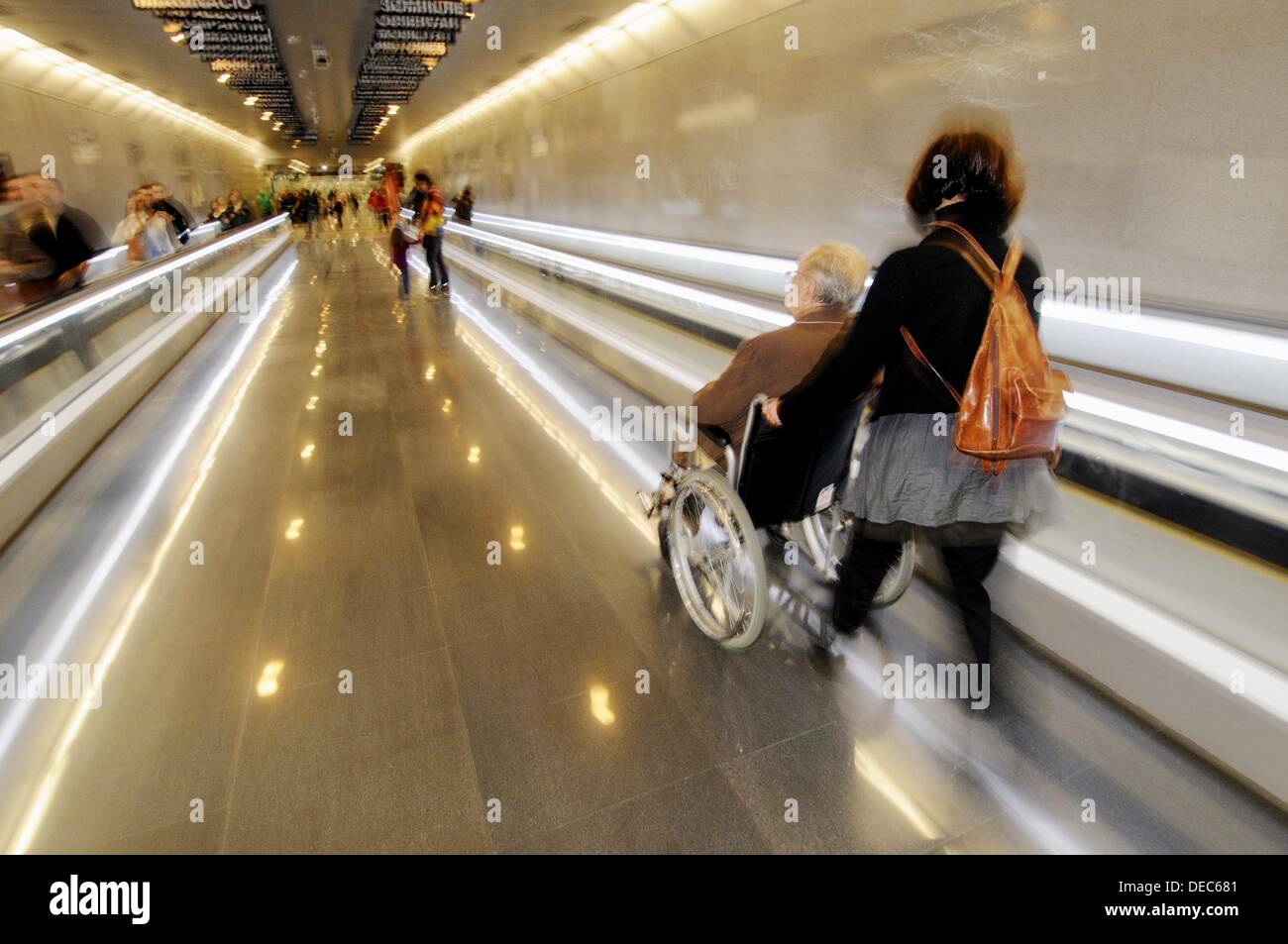 Woman carrying elderly man in wheelchair. Subway station, Barcelona, Catalonia, Spain Stock