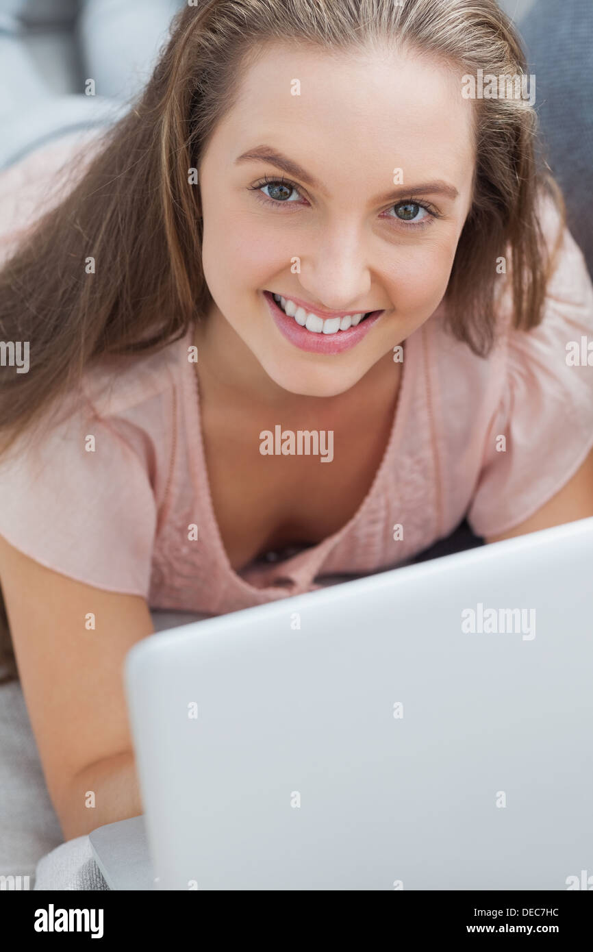 Woman lying on sofa with laptop Stock Photo