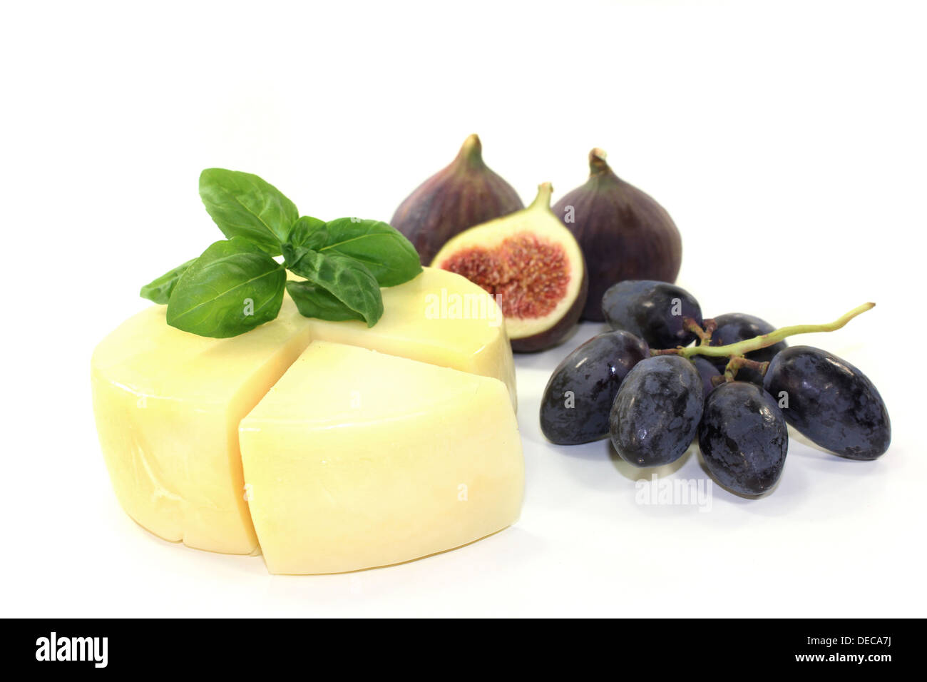 a piece of cheese with a cheese knife and basil Stock Photo