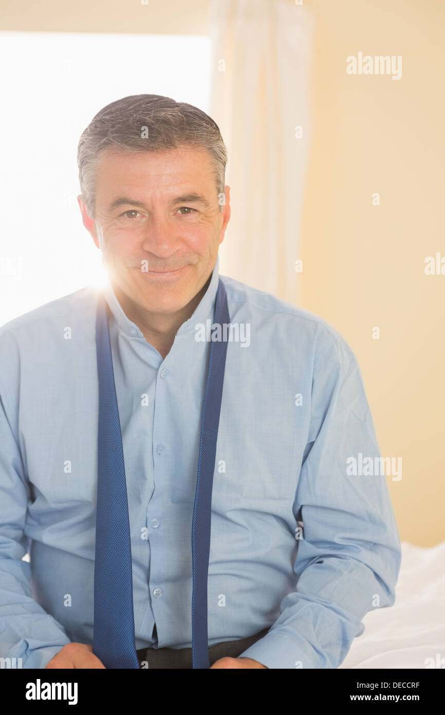 Happy man looking at camera sitting on a bed Stock Photo