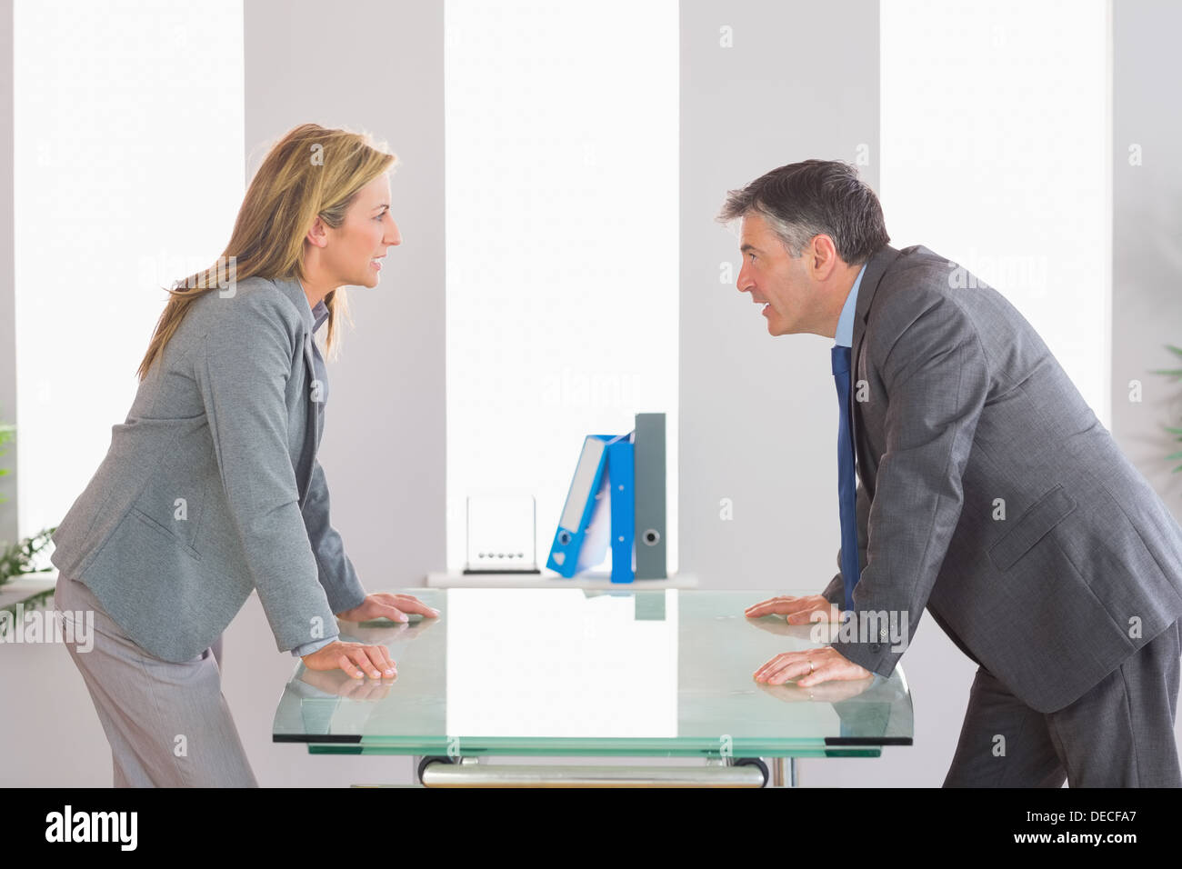 Two angry businesspeople arguing on each side of desk Stock Photo