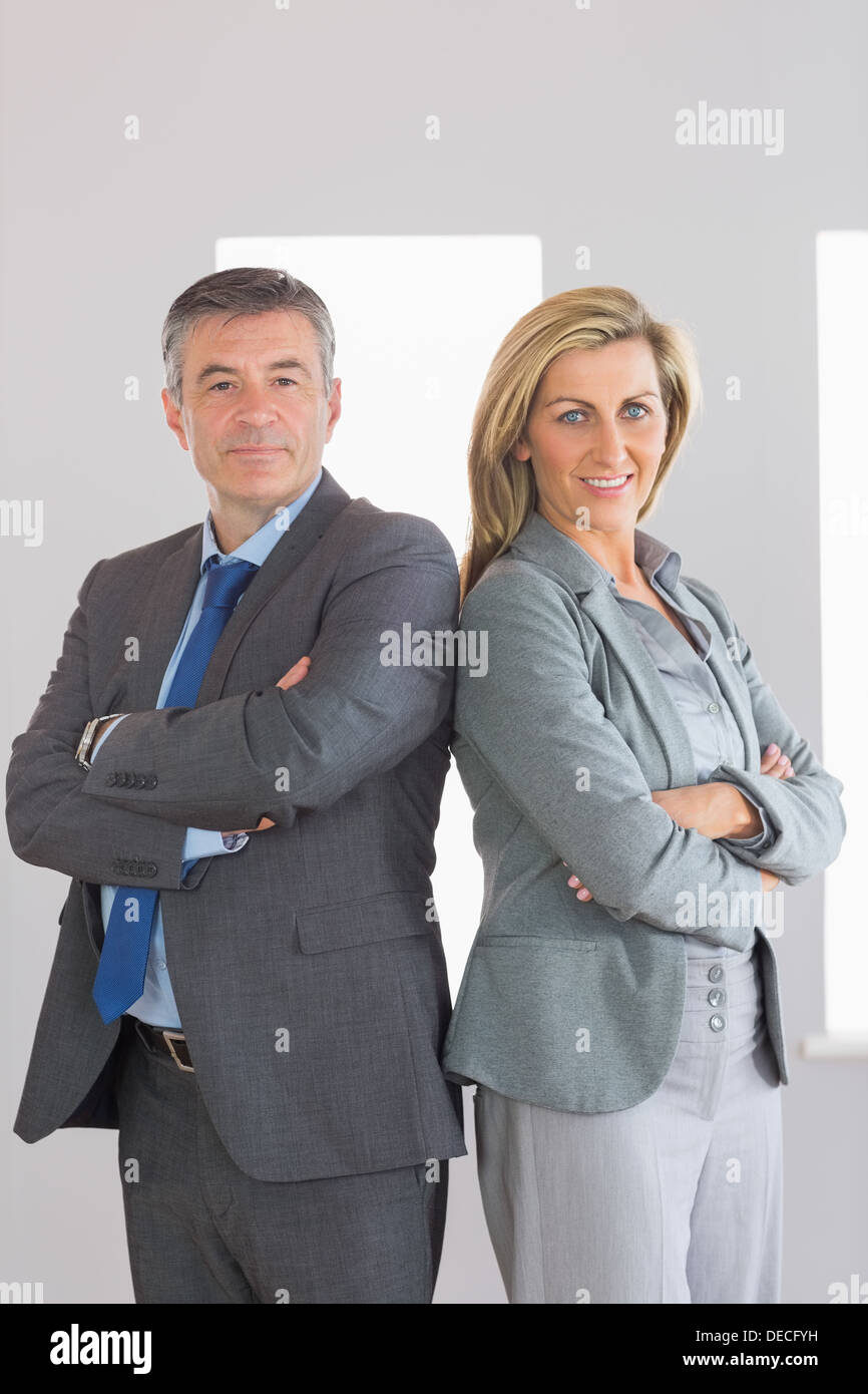 Two content businesspeople looking at camera standing back-to-back Stock Photo