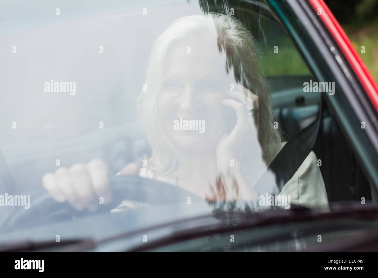 Cheerful mature woman on the phone driving red cabriolet Stock Photo