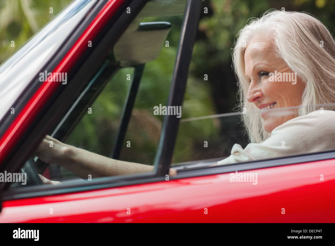 Cheerful mature woman driving red convertible Stock Photo