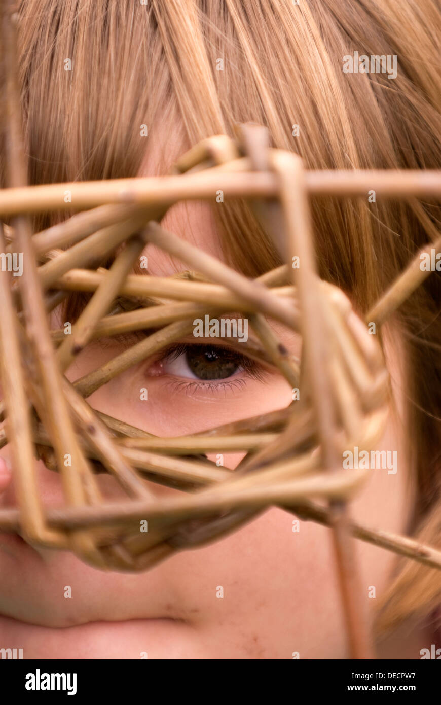 6 year old girl looking at a partially completed willow basket at a rural crafts event, Farnham, Surrey, UK. Stock Photo