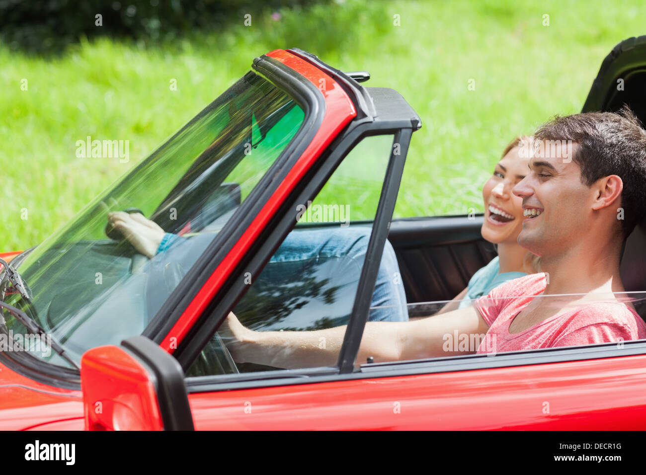 Smiling young couple having a ride in red cabriolet Stock Photo - Alamy