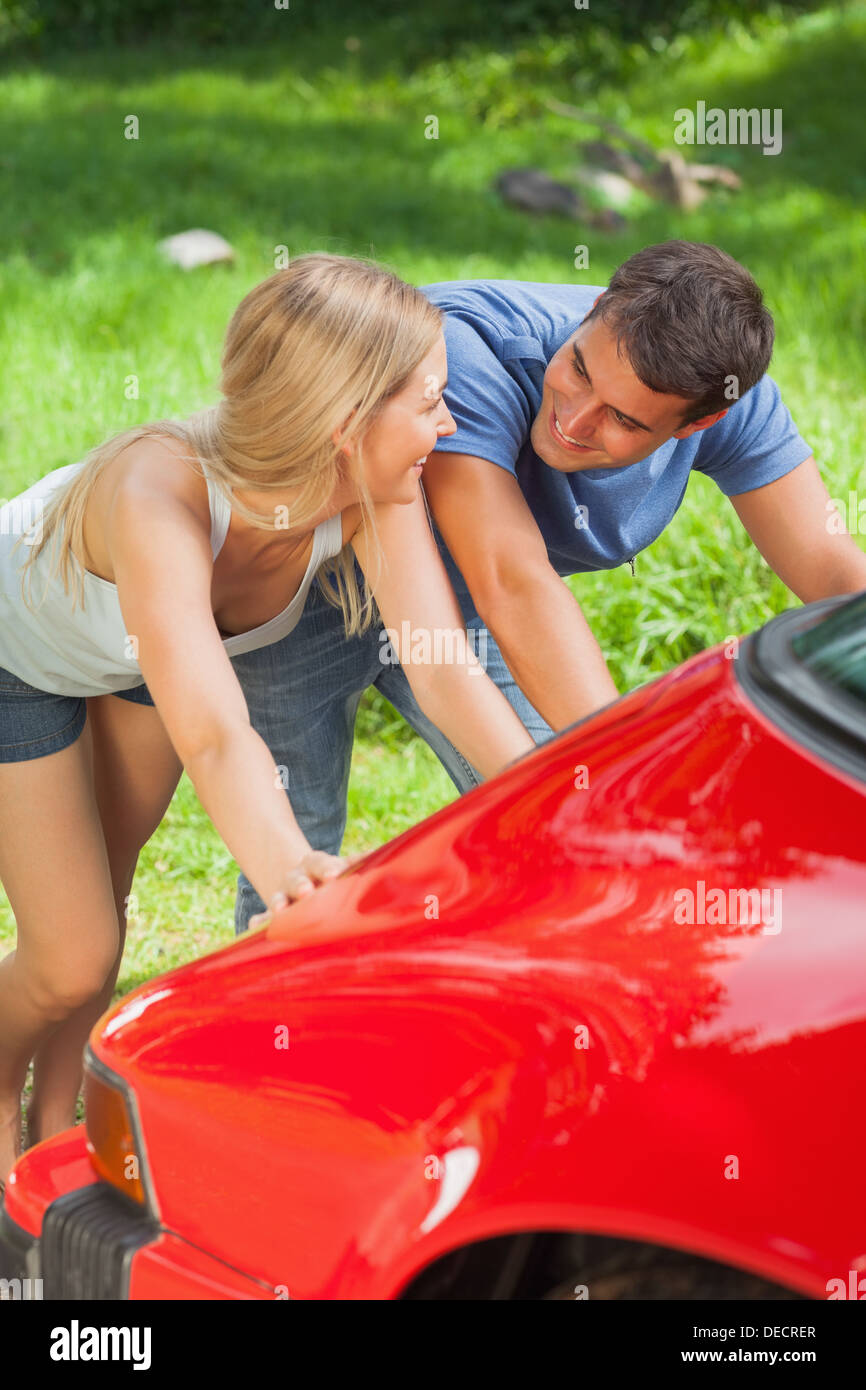 Happy couple pushing their broken down car Stock Photo