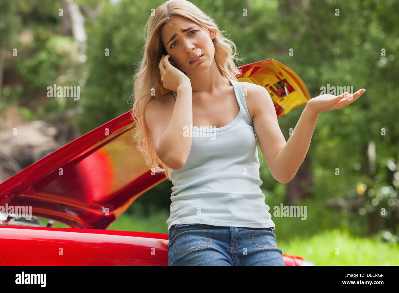 Desperate blonde calling for assistance after breaking down Stock Photo