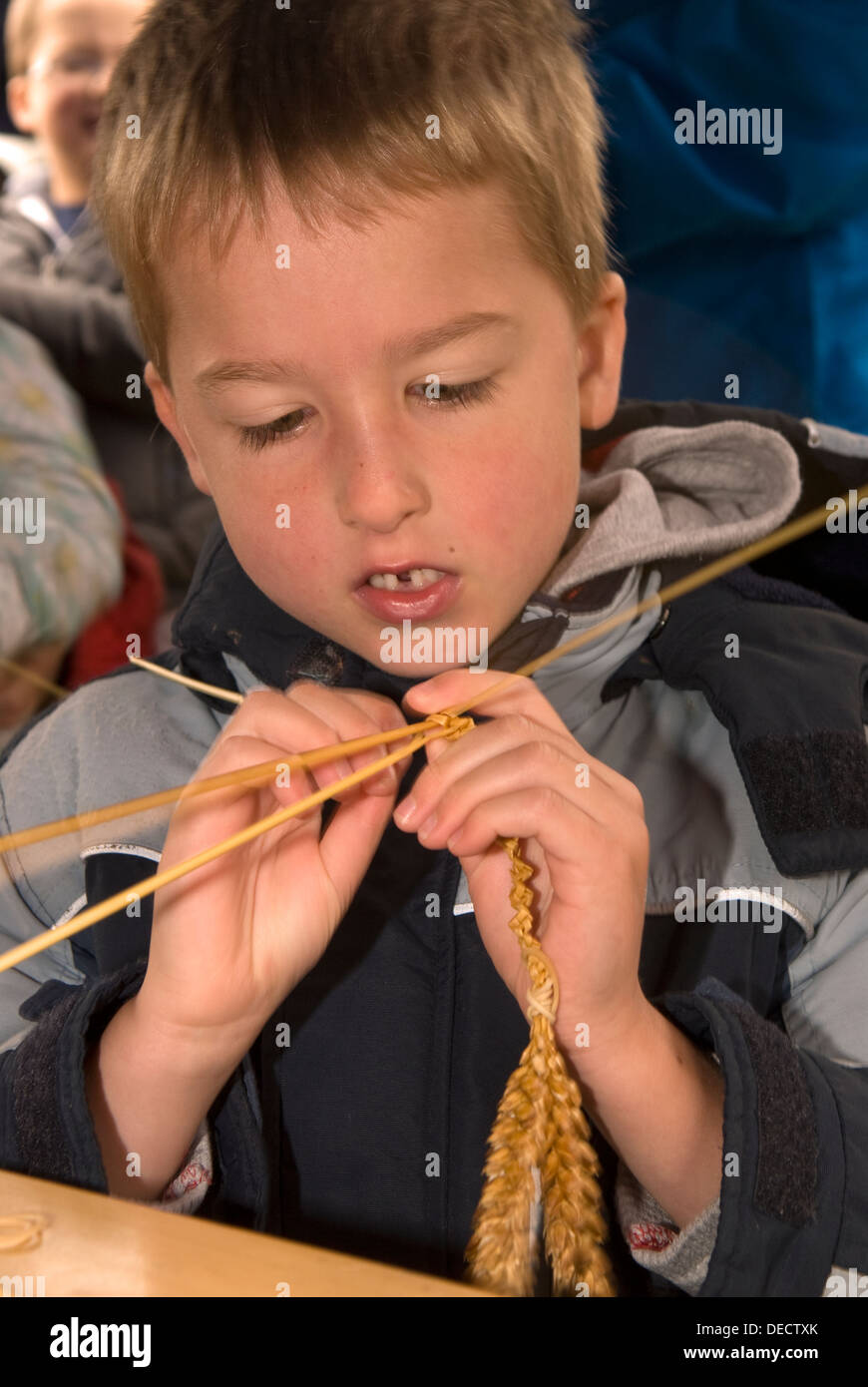 6 year old boy making a corn dolly at a heritage event day, Farnham, Surrey, UK. Stock Photo
