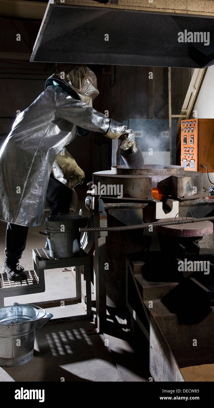 Gold room operator adding more gold and additives to tilting ore furnace before pouring into ingots, gold mine, Mauritania, Stock Photo