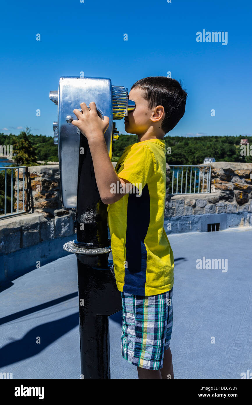A boy looking through a coin-operated public binocular at Fort Frederick/Fort William Henry historic site in Maine. Stock Photo